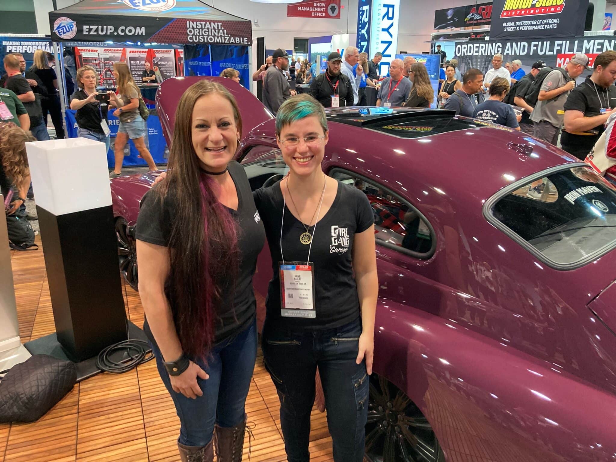 Bogi Lateiner (Girl Gang Garage) and Anne Pauley (Google) standing in front of the Iron Maven custom car-rebuild at SEMA 2022. (Image courtesy Anne Pauley.)